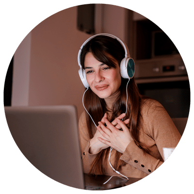 Une photo d’une femme souriante avec des écouteurs devant son ordinateur heureuse de bénéficier d’un accompagnement personnalisé