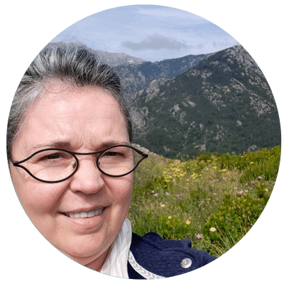 Julie Lamarque, une passionnée de la nature et du bien-être, cueille des fleurs sur un chemin de montagne corse pour préparer ses onguents de massage.
