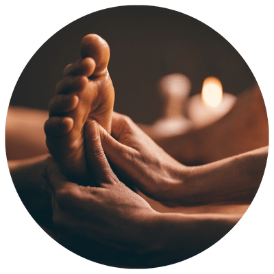 Une personne reçoit un massage des pieds avec des mains qui appuient sur des points précis de la plante des pieds.