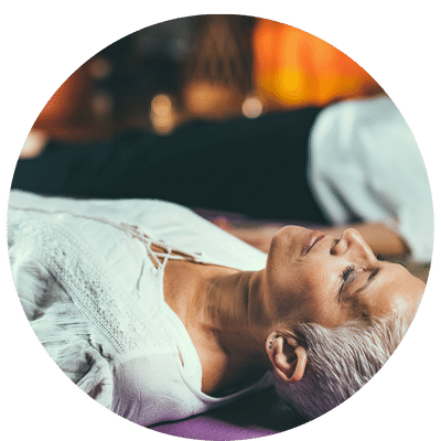 Des personnes allongées sur des tapis de yoga, avec des couvertures et les yeux fermés, qui reçoivent un soin énergétique pléadien de groupe